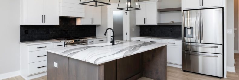 light blonde wood floors, white cabinets, black back splash, stainless steel appliances, white and gray marble countertops and hanging black iron light fixtures