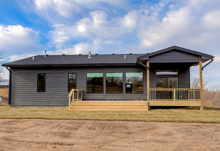 Black House Rear Exterior Rear Exterior of home with wood deck, dark gray siding and black roof