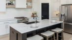 kitchen with light wood flooring, white cabinetry, white marble counter and stainless steel appliances