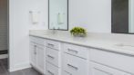 double vanity bathroom, white cabinetry, large gray tile floors to walk-in shower with white subway tile