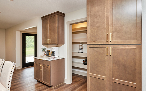 wood upper and lower cabinets in kitchen looking into walk-in pantry