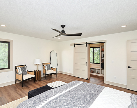 bedroom with sitting area, cream walls, taupe trim and sliding barn door to closet