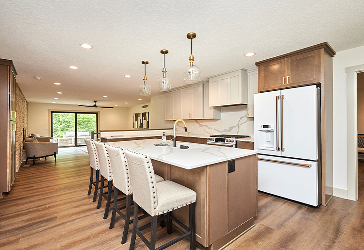 kitchen with taupe upper cabinets, wood lower cabinets, white stove and refrigerator with gold hardware, matching stone counter and backsplash wall, wide wood plank flooring